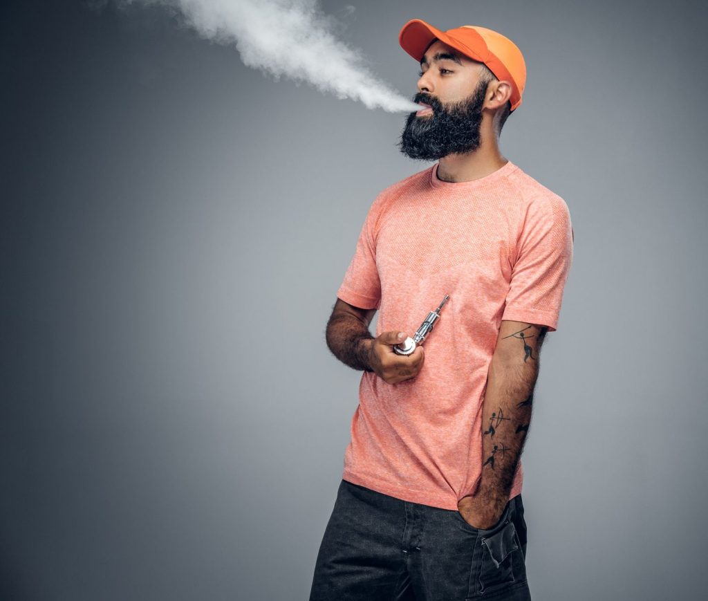 Man wearing pink with orange cap holding a pipe and smoking tobacco shop in Tulsa