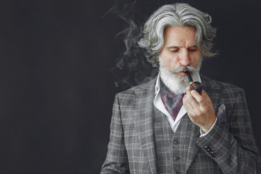 An elderly man smoking tobacco in a wooden pipe at tobacco store in Tulsa