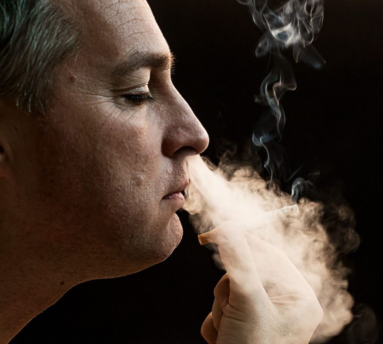 A profile of a man in his side view smoking in a Cigar Shop in Tulsa
