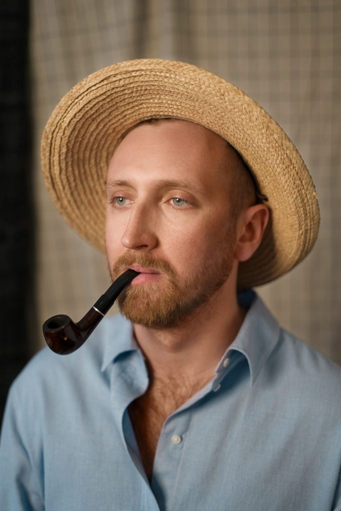 A man wearing straw hat smoking a Glass pipe near Milwood Estate