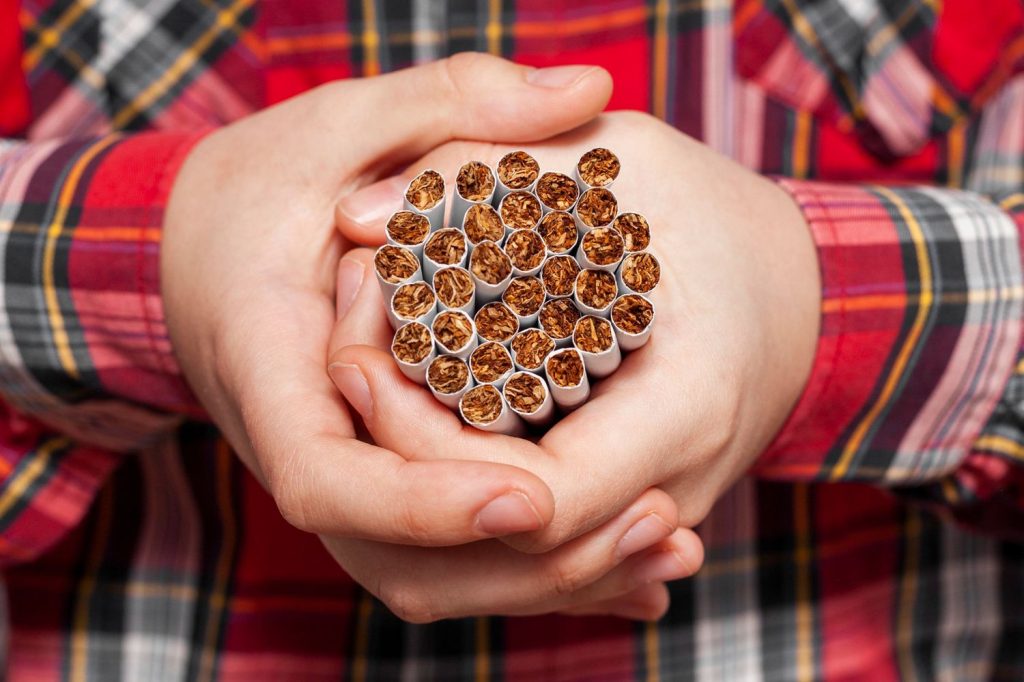 A man wearing a plaid shirt holding a bundle of premium cigars in a cigar shop at Executive Estate