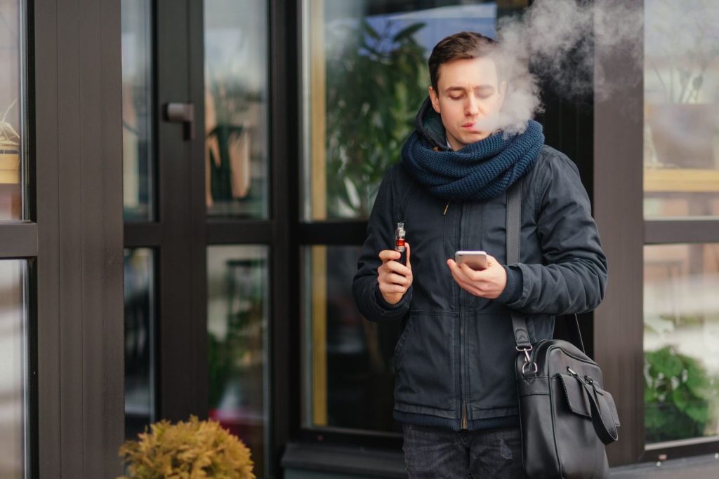 An image of a Vape shop in Stevenson of a man with scarf holding a phone while smoking