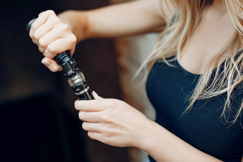 Woman in black refilling vape juice at Cloud Dreamzzz Smoke Shop, vape supplies near Milwood Estate