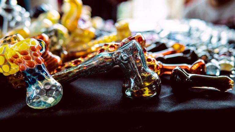 A vibrant assortment of colorful hand-blown glass pipes Tulsa with bubble designs on a black table display.