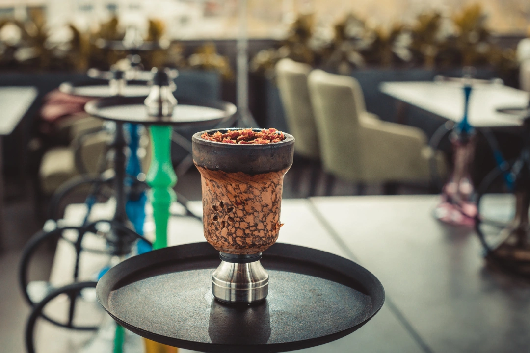 Hookah Shop Tulsa—clay bowl with flavored tobacco and vibrant hookah stems in upscale lounge environment