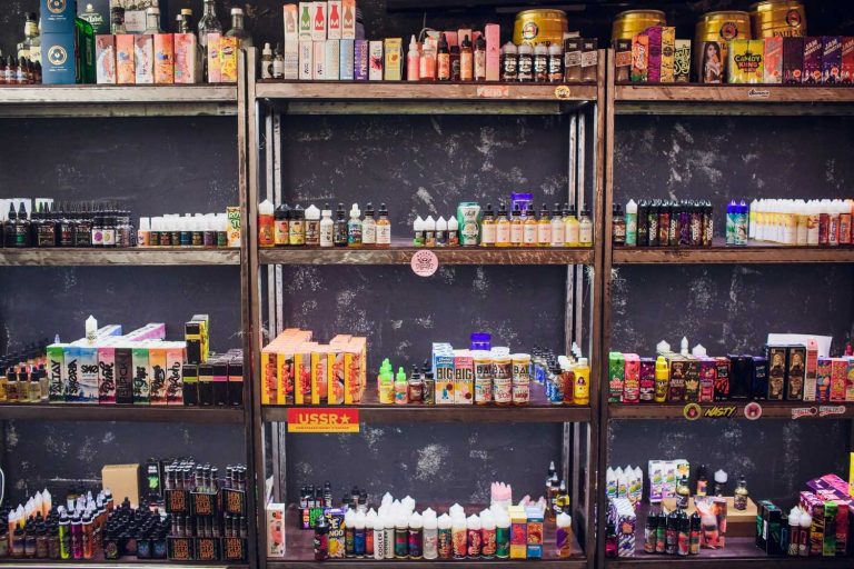 Shelves stocked with colorful e-liquid bottles and vape products like Nasty and USSR brands in a vibrant smoke shop Tulsa, offering diverse flavors for vaping enthusiasts.
