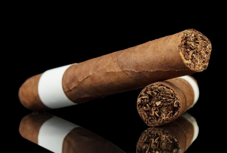 Two brown cigars with white bands on black reflective surface, product showcase for Cigar Shop Tulsa premium tobacco.