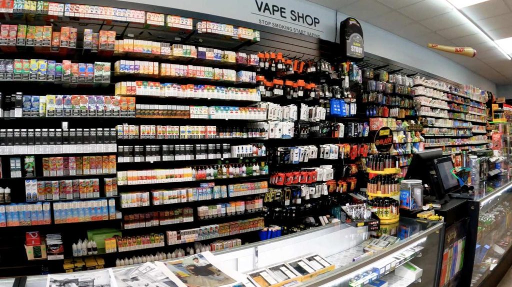 Expansive interior view of a vape shop with endless shelves of e-juices, devices, and accessories under a 'Stop Smoking Start Vaping' sign at smoke shop Tulsa.