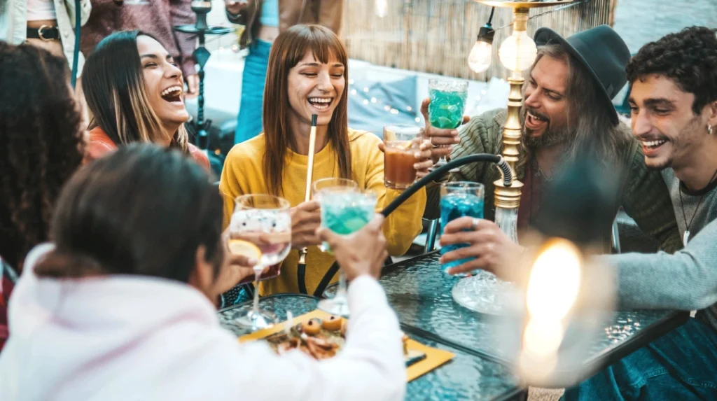Hookah Shop Tulsa—group socializing with drinks, food, and hookah in festive outdoor lounge setting