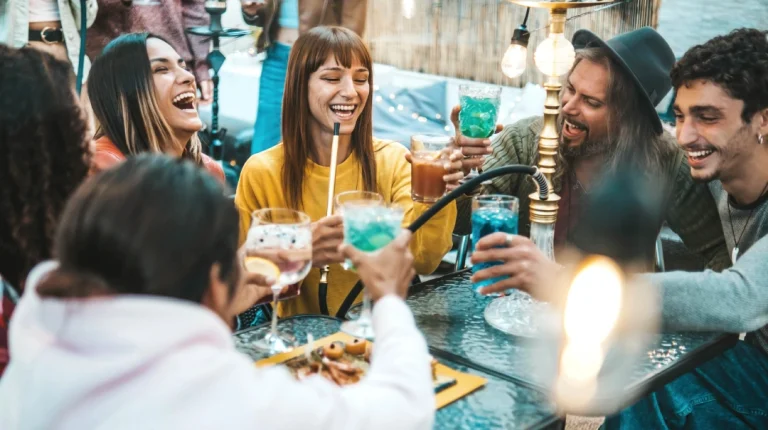 Hookah Shop Tulsa—group socializing with drinks, food, and hookah in festive outdoor lounge setting