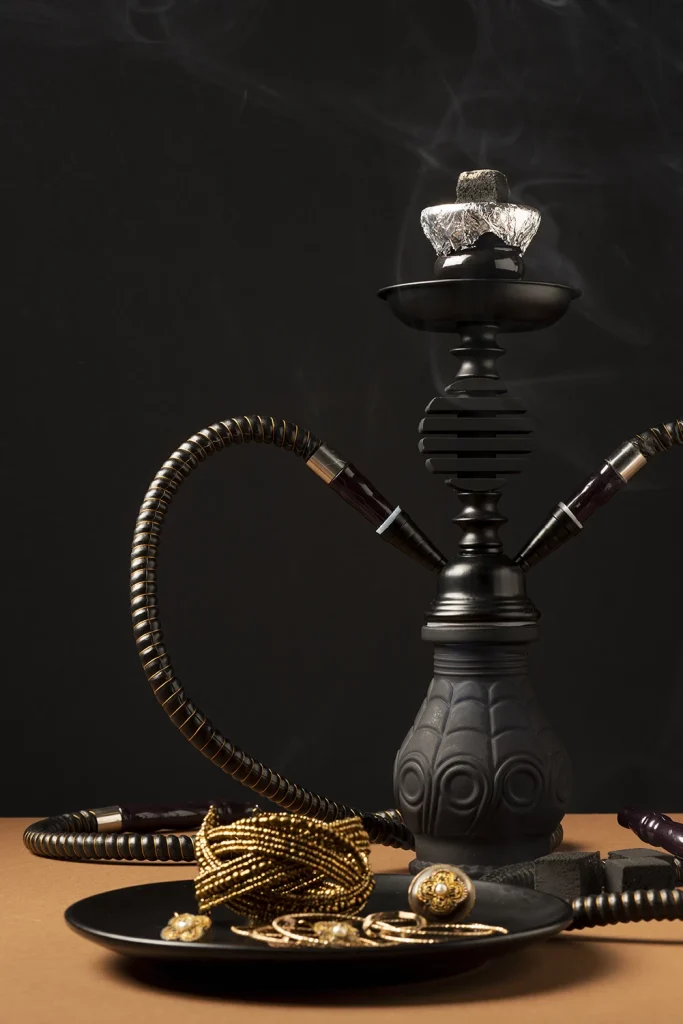 Black hookah with gold jewelry on a plate, highlighting luxury items at a hookah shop in Tulsa.