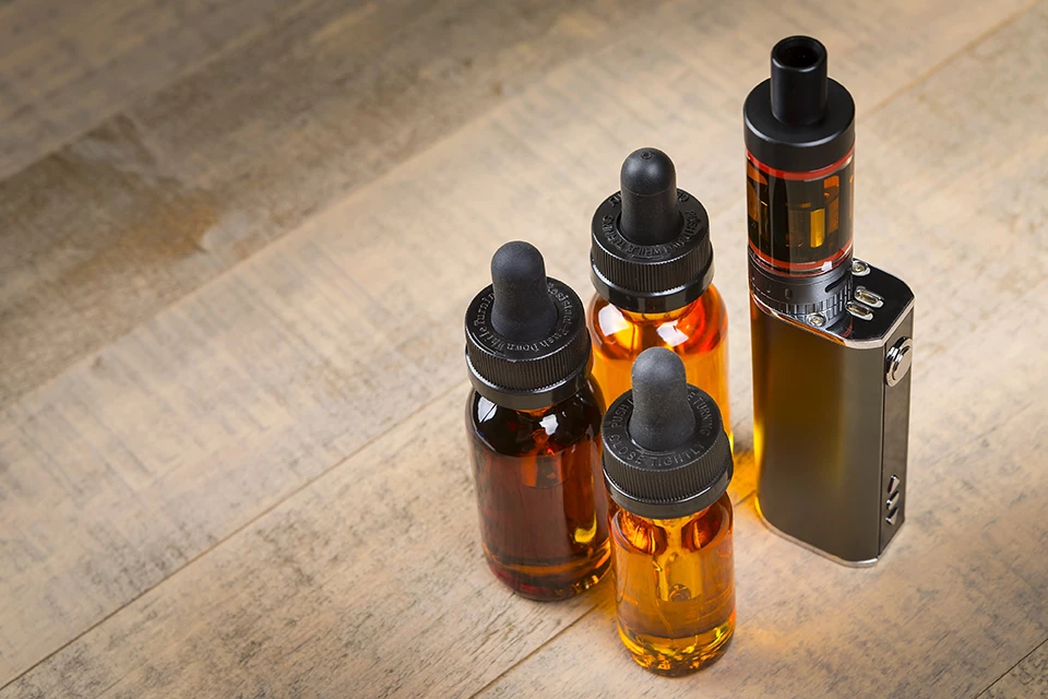Assorted vaping devices and e-liquid bottles displayed on a wooden surface at a head shop in Tulsa.