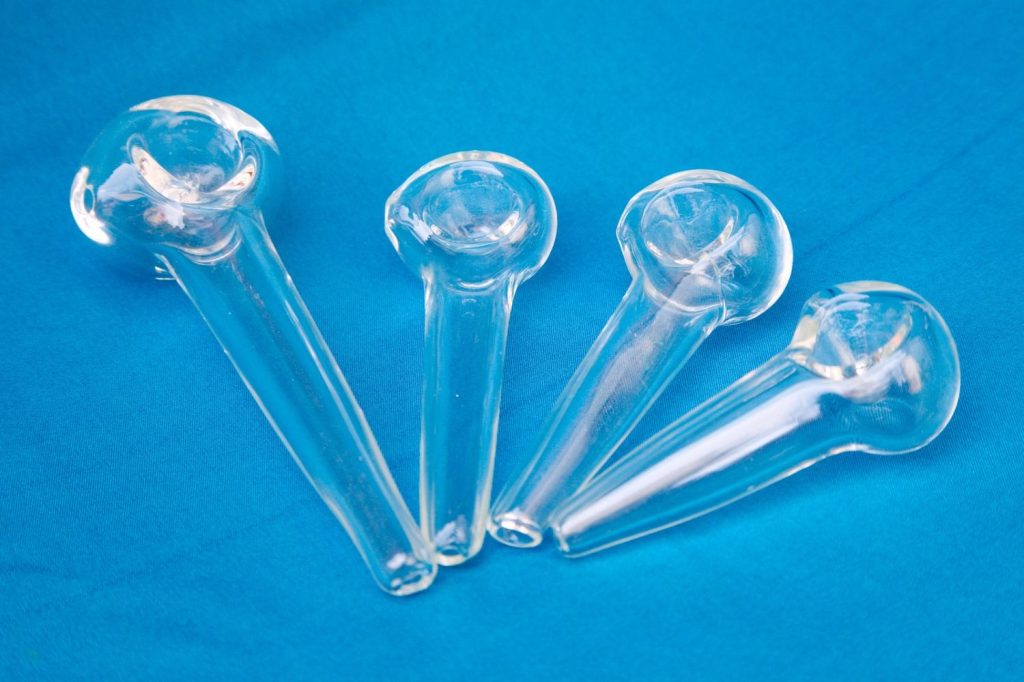 Clear glass pipes in various sizes arranged on a blue background at a modern smoke shop Tulsa, showcasing simple yet elegant smoking tools.