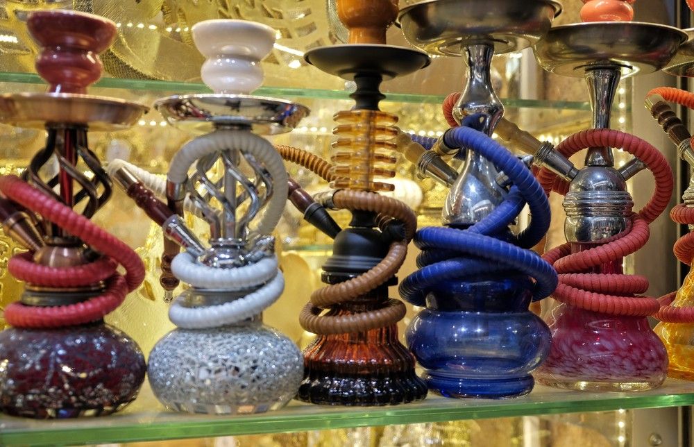 Colorful hookahs with coiled hoses displayed on glass shelves at Smoke Shop Tulsa offering premium shisha accessories