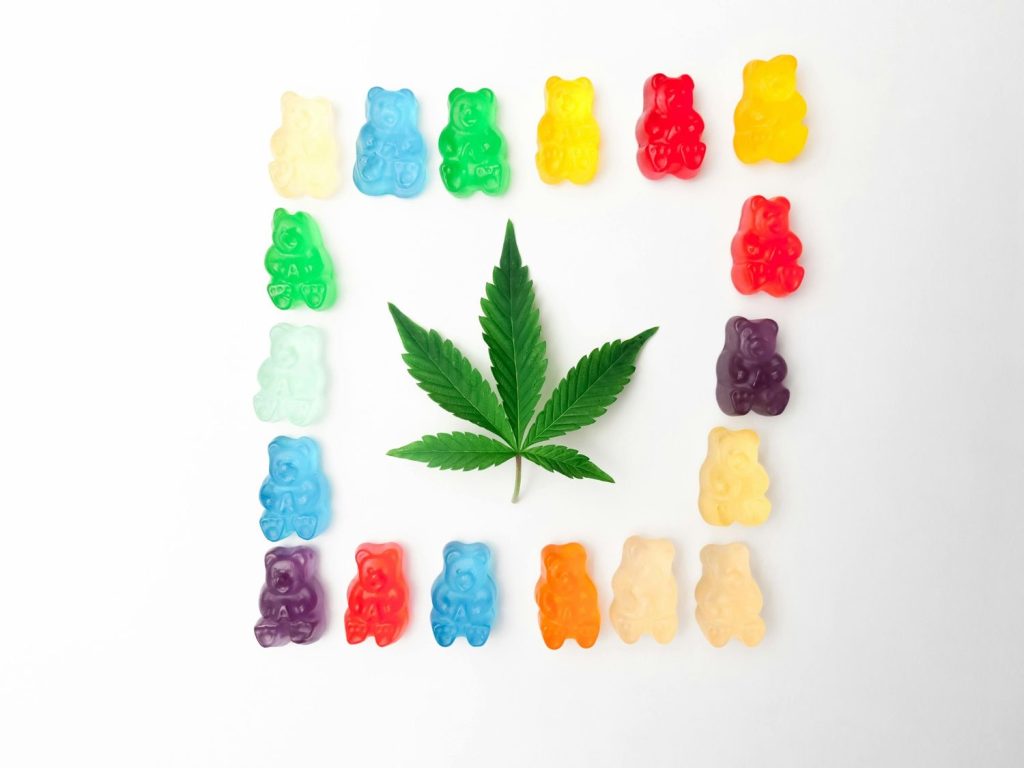 Colorful CBD/Delta 8 gummies and a hemp leaf, available at your local delta 8 store tulsa.