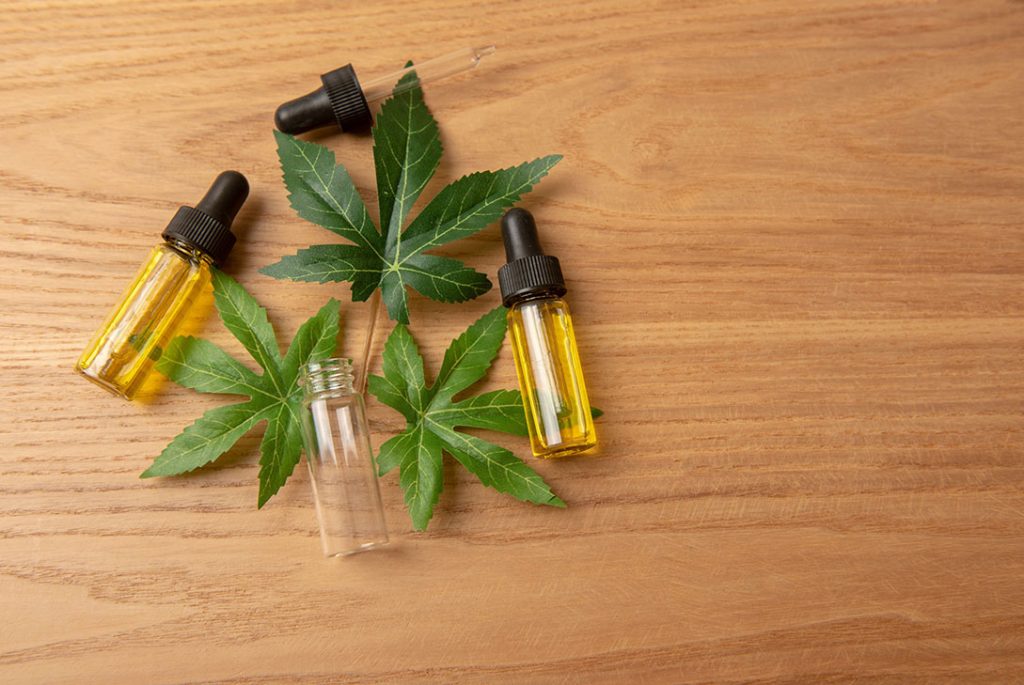 Natural hemp-derived CBD oil flat lay featuring a bottle and leaf, your trusted cbd store tulsa.