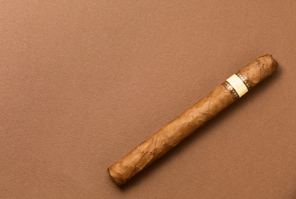 A premium hand-rolled single cigar on a rich brown background, available at a leading cigar shop in Tulsa, Oklahoma.