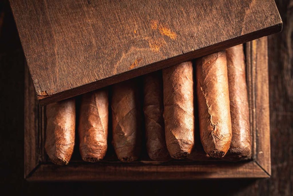 Premium cigars stored inside a dark wooden humidor, a high-quality selection available at a top-rated cigar store Tulsa.