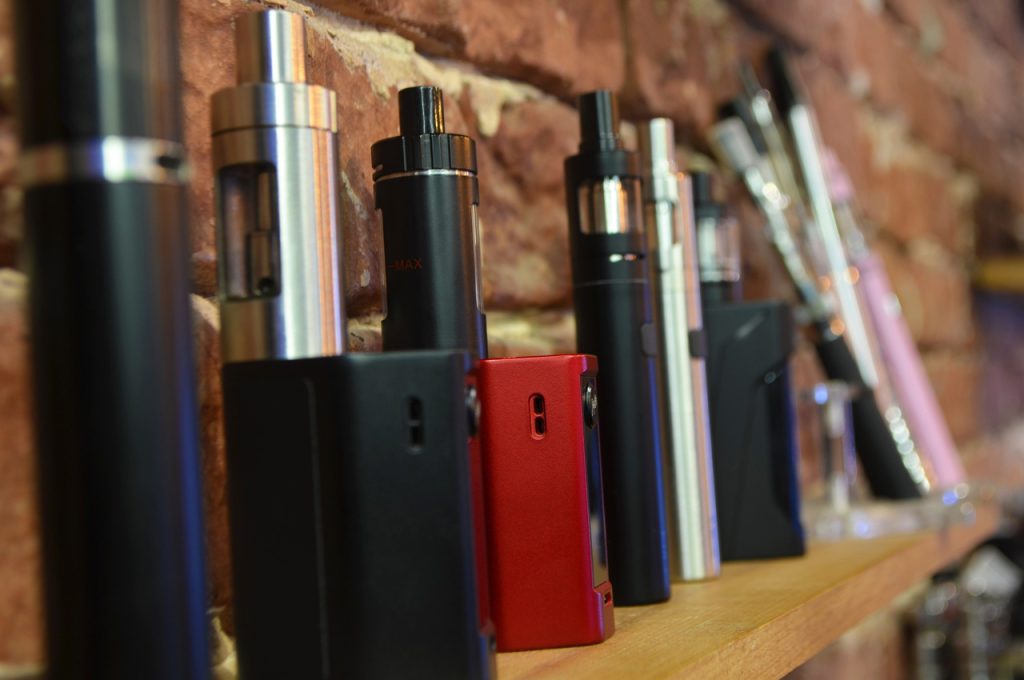 Close-up of various electronic cigarettes and pod systems on display shelves inside a local smoke shop Tulsa.