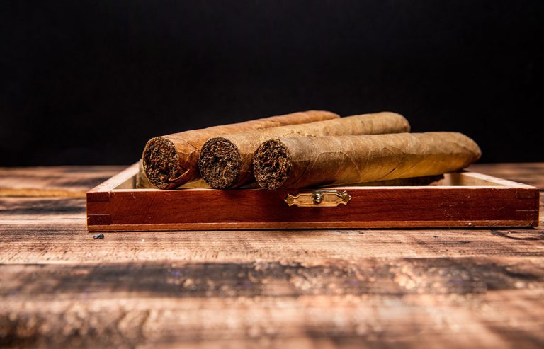 Three hand-rolled, light-leaf premium cigars displayed on a wooden surface, highlighting the refined selection at a cigar store Tulsa.