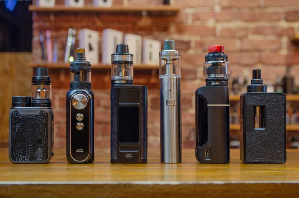 High-quality vape mods and tanks on a wooden counter at a smoke shop Tulsa, featuring premium hardware brands.