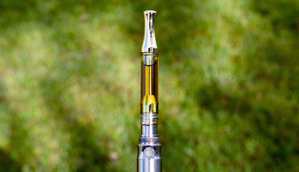 Silver vape cartridge with clear oil on a chrome battery highlighting the high quality vape mods Tulsa has nearby.