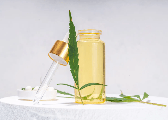 Premium yellow CBD oil tincture bottle and dropper with a fresh hemp leaf at a local CBD shop Tulsa dispensary.
