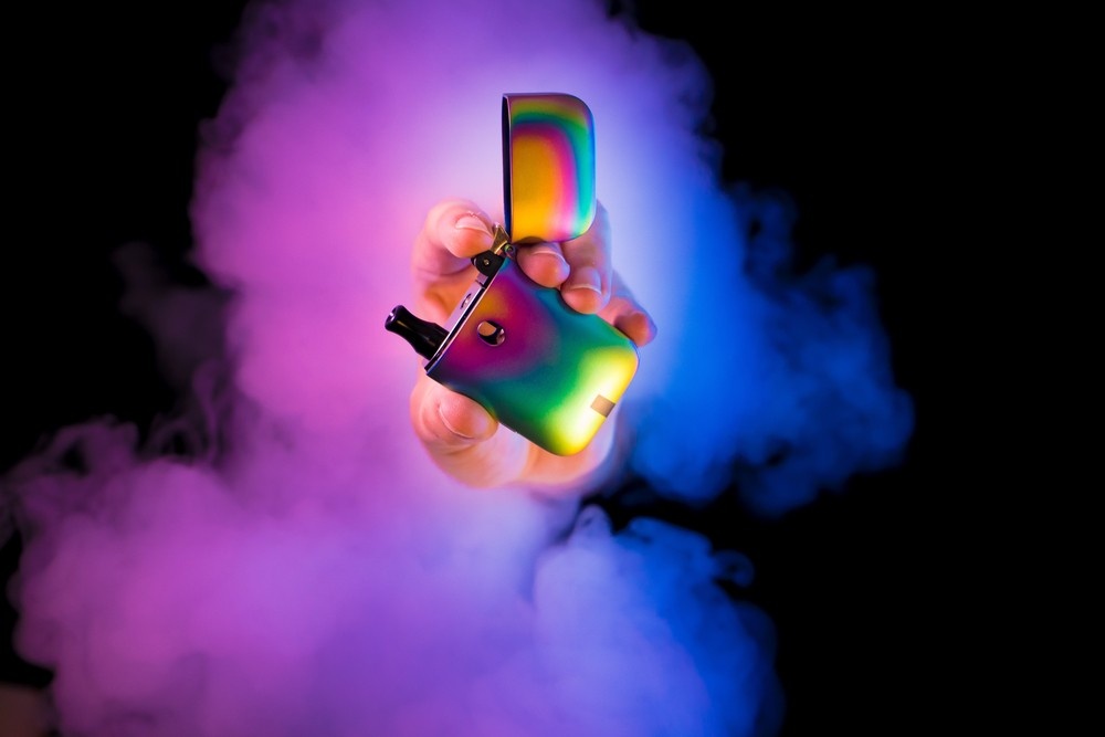 Close-up of a unique rainbow e-cigarette, highlighted by pink and blue smoke. Explore custom e-cigarettes Tulsa.