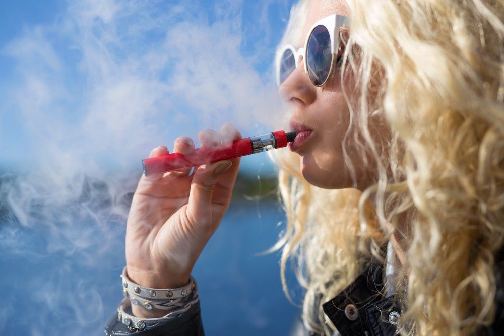 A close-up view of a person using an electronic cigarette, creating dense vapor clouds like a vape store Tulsa scene. 