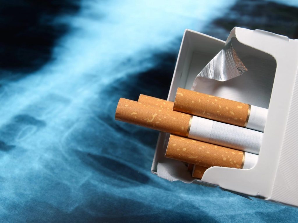Pile of loose tobacco cigarettes with orange filters on a weathered wooden surface at a cigarette shop Tulsa. 