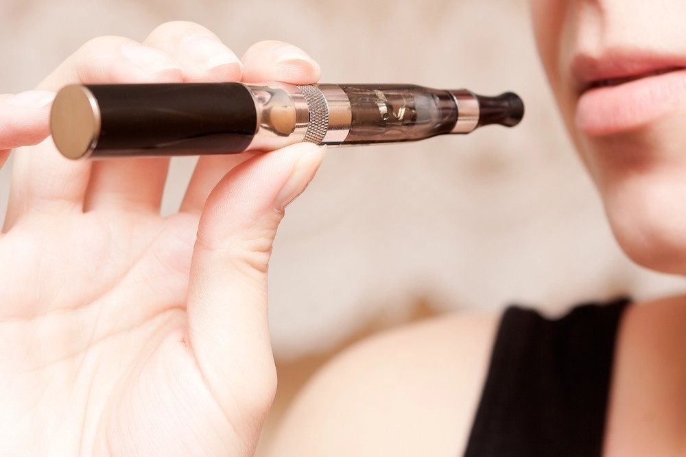 Close-up of a hand holding a pen-style e-cigarette device to the lips for a person looking at e-cigarettes tulsa.