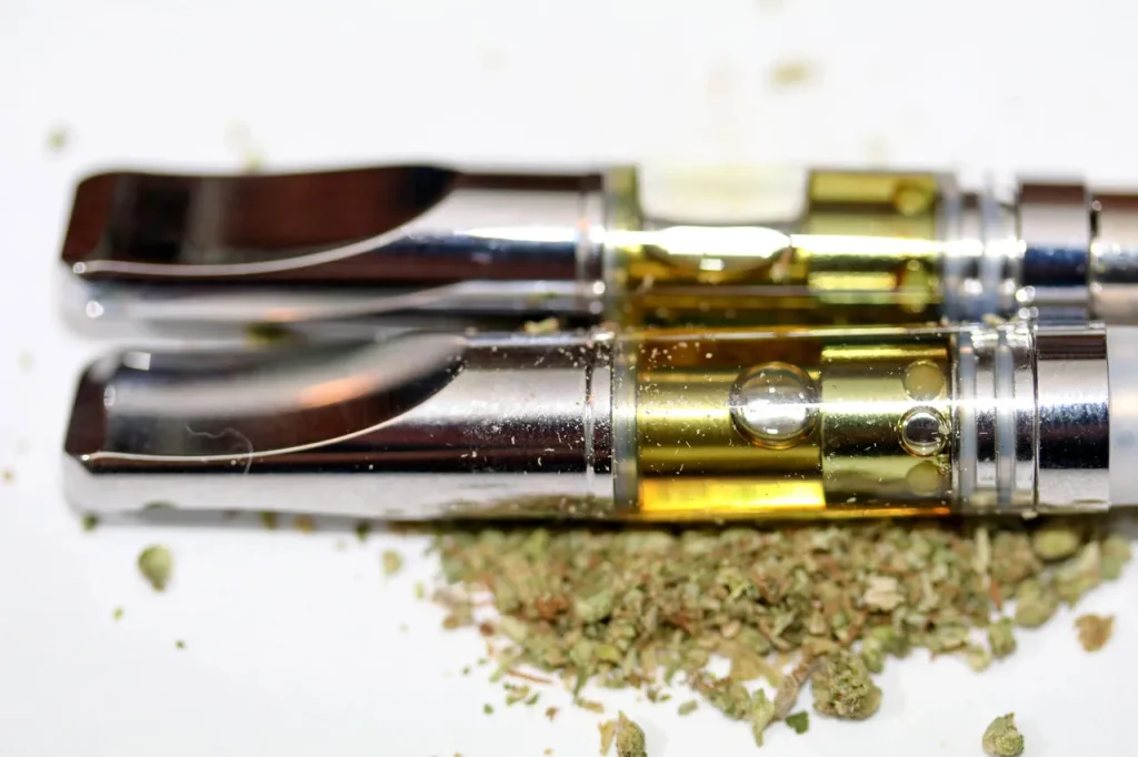 Premium THC concentrate cartridges resting on loose flower, featuring top-tier herbal vaporizers Tulsa gear.