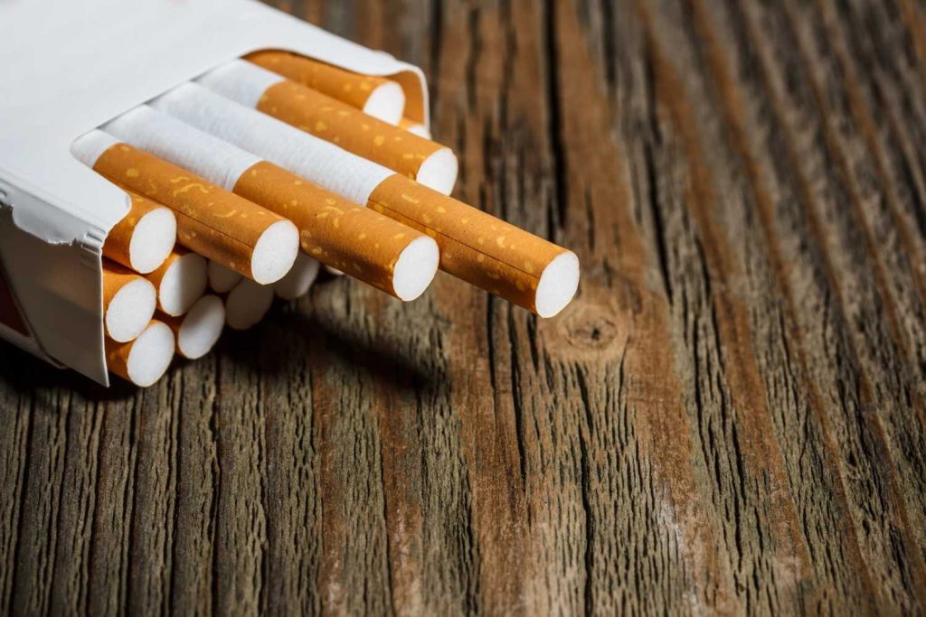 A close up of a premium cigarette pack with filters on a rustic wood table at a local cigarette shop Tulsa.