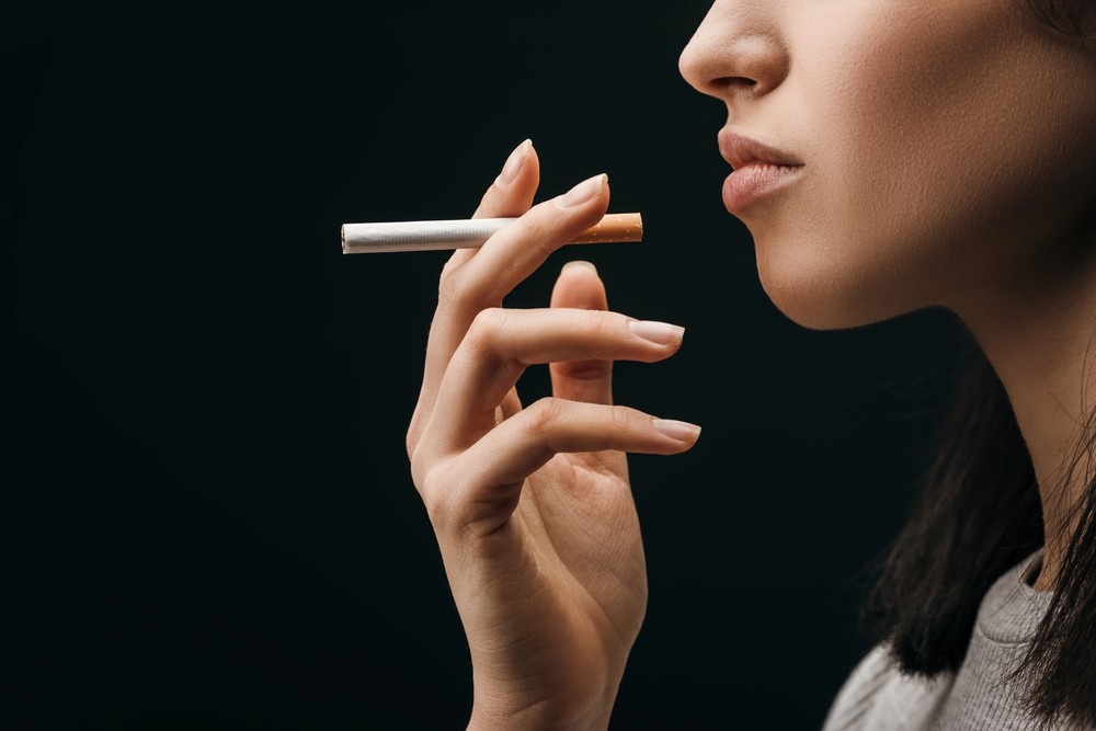 A woman in profile holds a lit cigarette. A top tobacco shop tulsa provides all your quality smoking needs.
