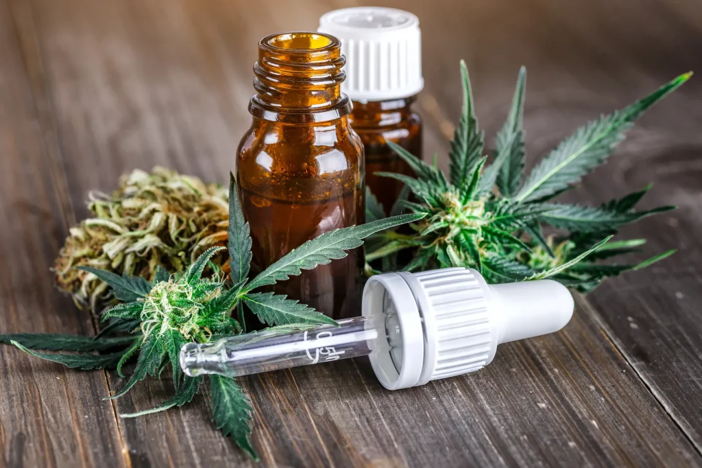 Amber CBD oil bottle, glass dropper, and cannabis leaves on wood. Discover high-quality options at our cbd shop tulsa.