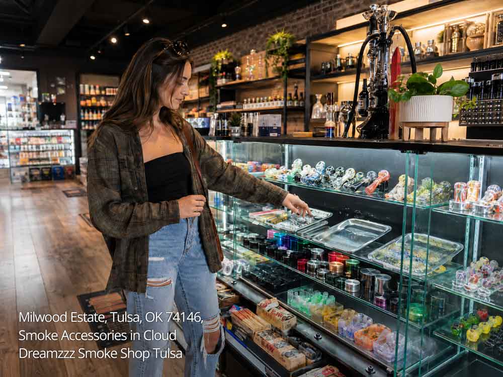 A woman browses premium smoke accessories in a Tulsa shop, looking at pipes and glass items inside a display case.